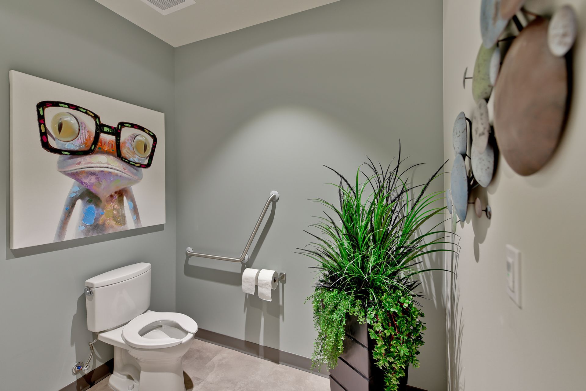 There is a picture of a frog on the wall above the toilet in the bathroom.