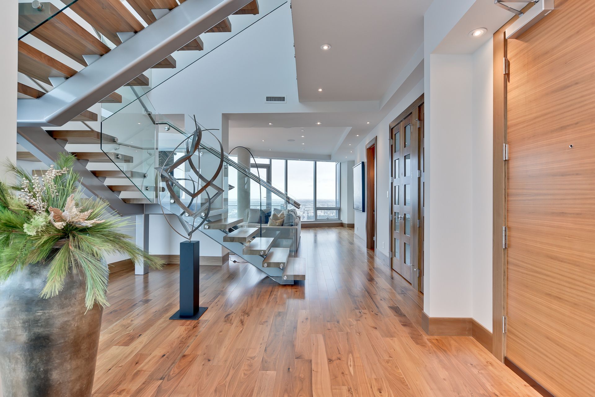 A hallway with hardwood floors and a staircase in the background