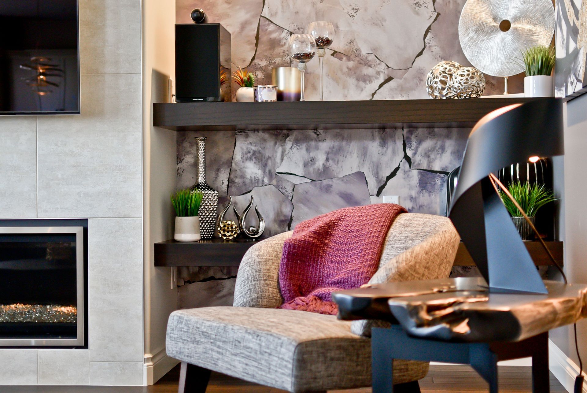 A living room with a fireplace and a chair with a pink blanket on it