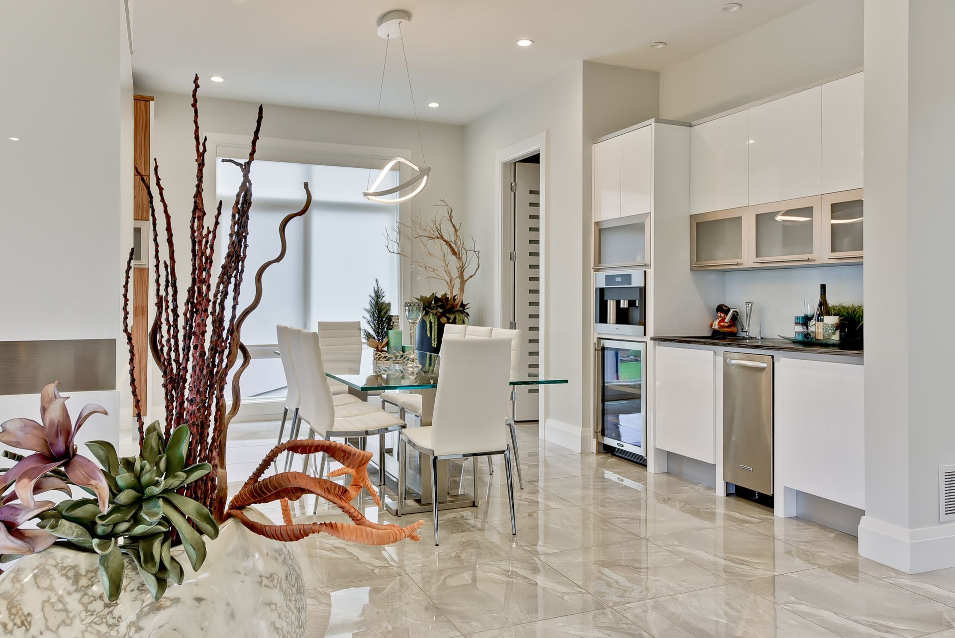 A kitchen and dining room with white cabinets and marble floors