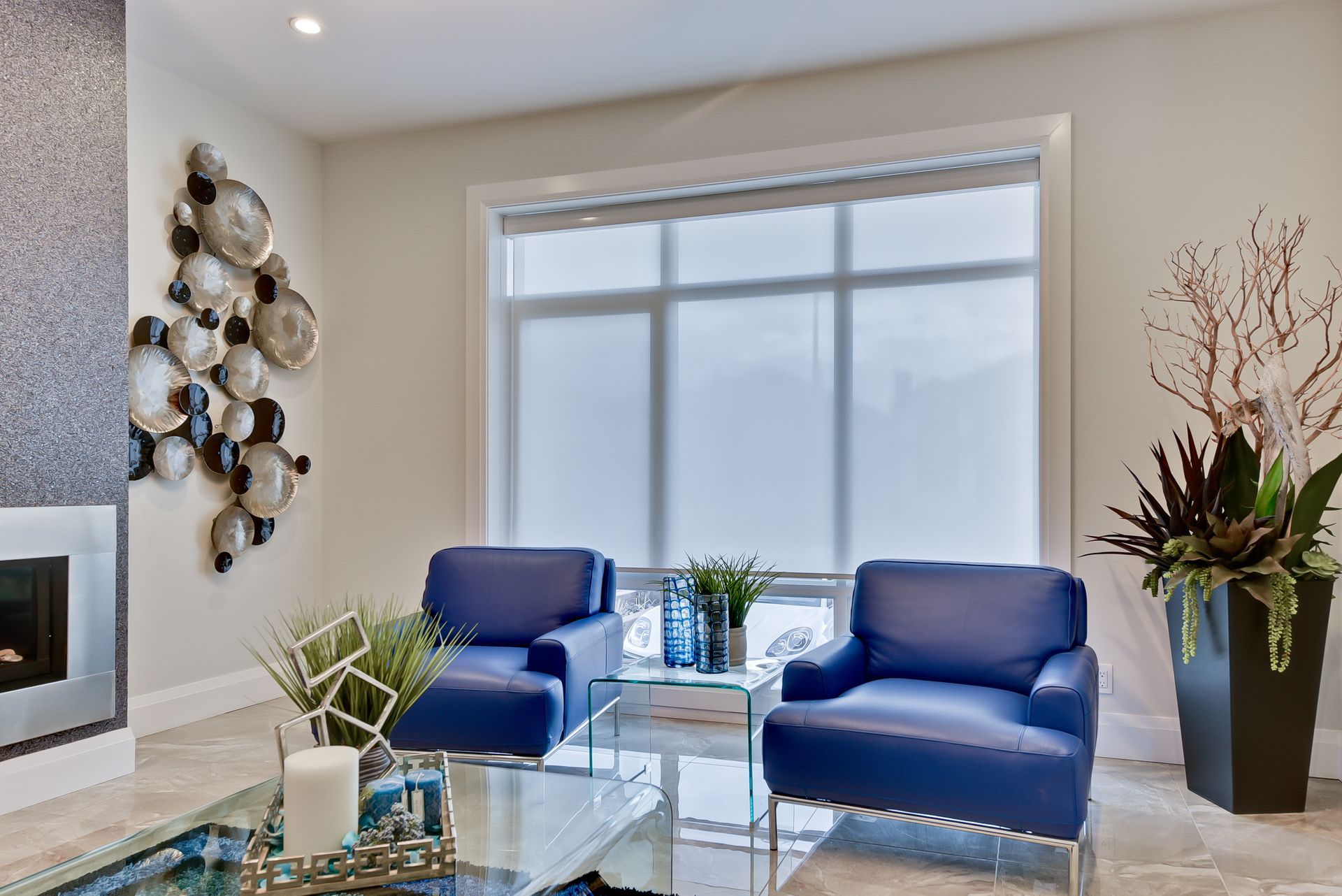 A living room with two blue chairs , a coffee table , and a fireplace.