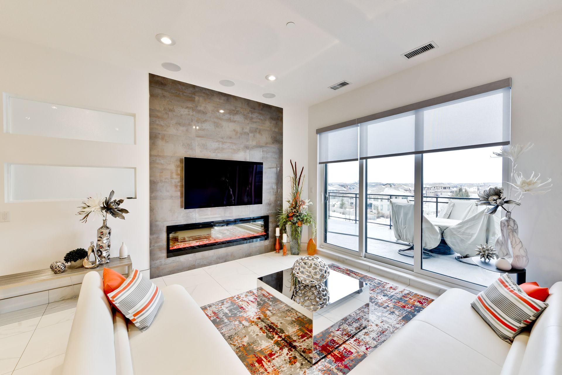 A living room with a couch , fireplace , television and large windows.