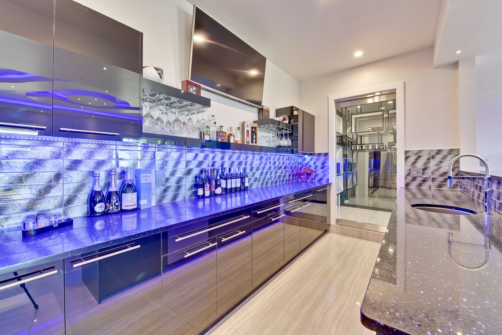 A kitchen with a bar and bottles of alcohol on the counter.
