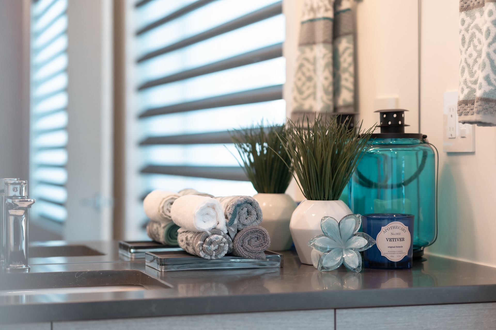 A bathroom counter with towels , candles , and a sink.
