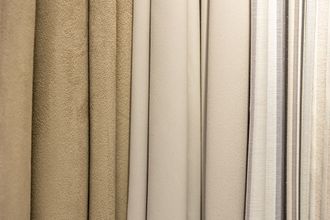 Close-up of beige and tan fabric swatches, varying textures, vertical.