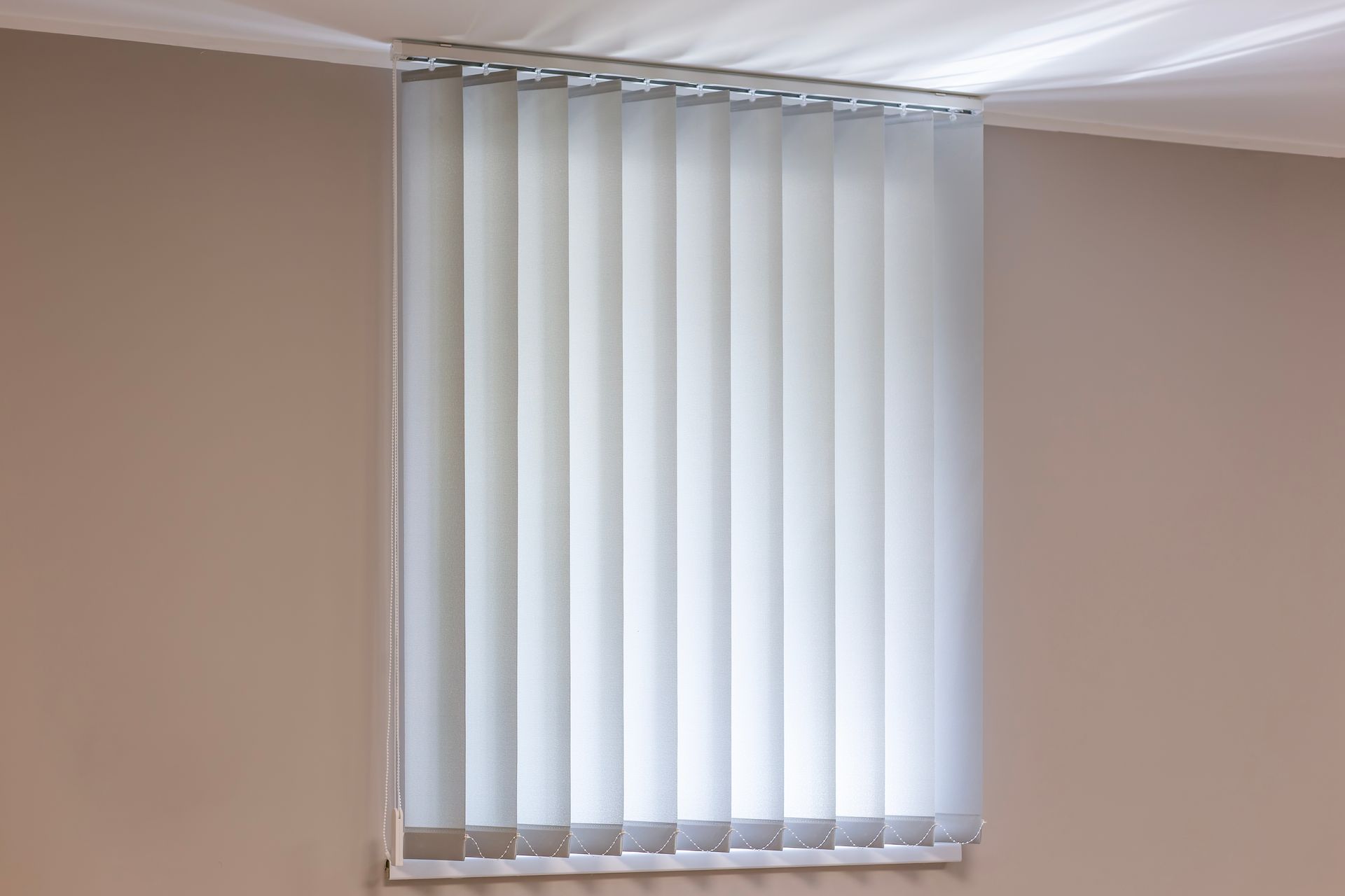 Vertical blinds on a window, beige walls, white ceiling.