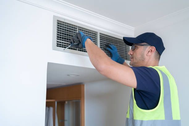 Two UV light lamps glow blue inside an HVAC unit above a warning sign about eye damage and an air flow arrow.