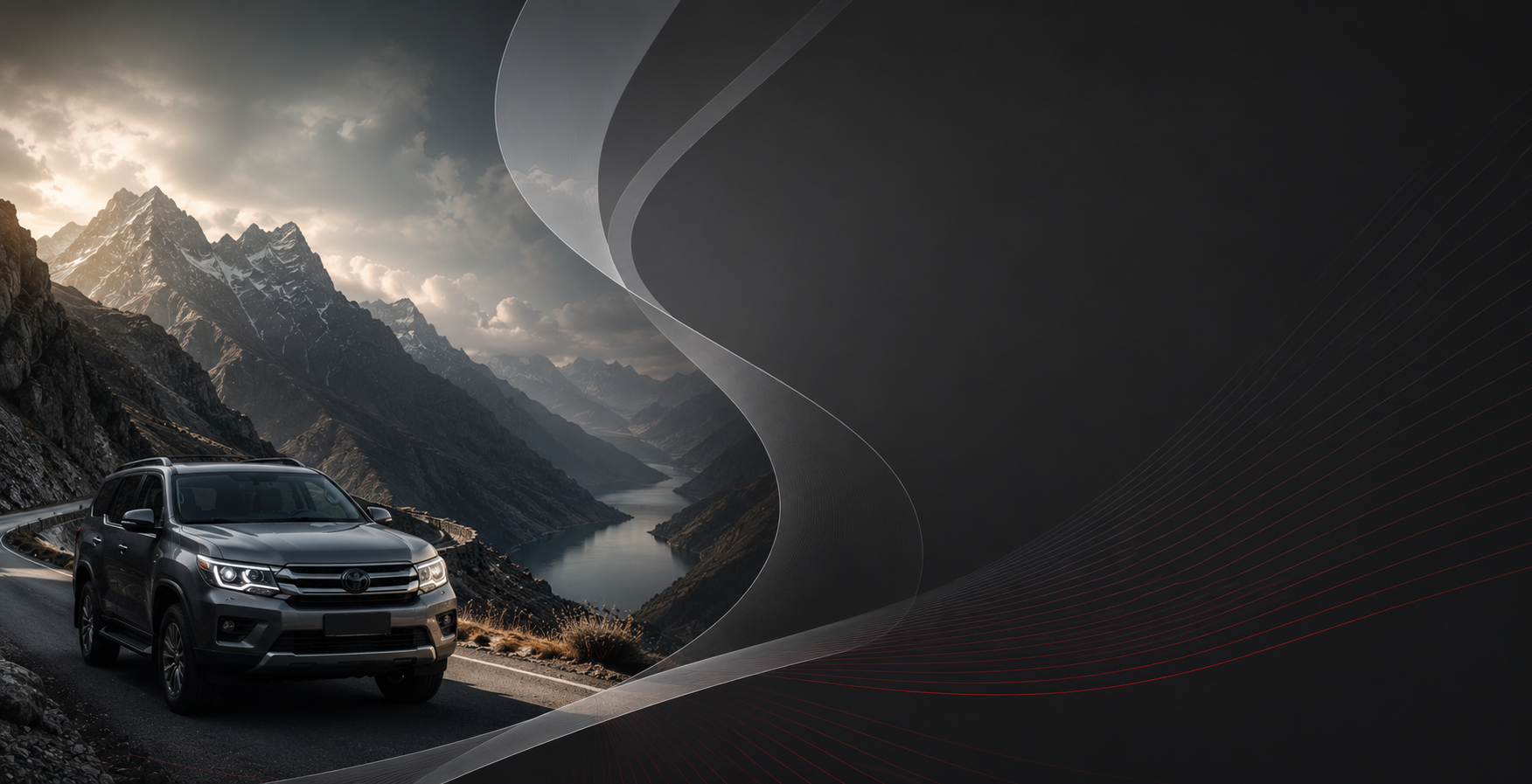 SUV negro en una sinuosa carretera de montaña bajo dramáticos picos grises y nubes.