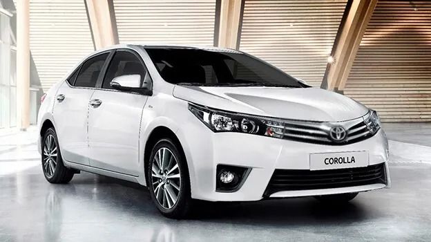 Un sedán Toyota Corolla blanco estacionado en el interior de una sala de exposición.