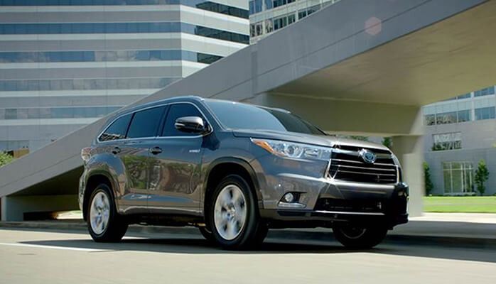 SUV gris oscuro estacionado frente a un edificio de oficinas moderno.