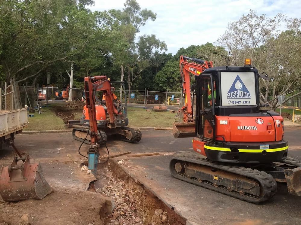 A Couple of Construction Vehicles Are Parked on the Side of the Road — Ausplumb NT in Winnellie, NT