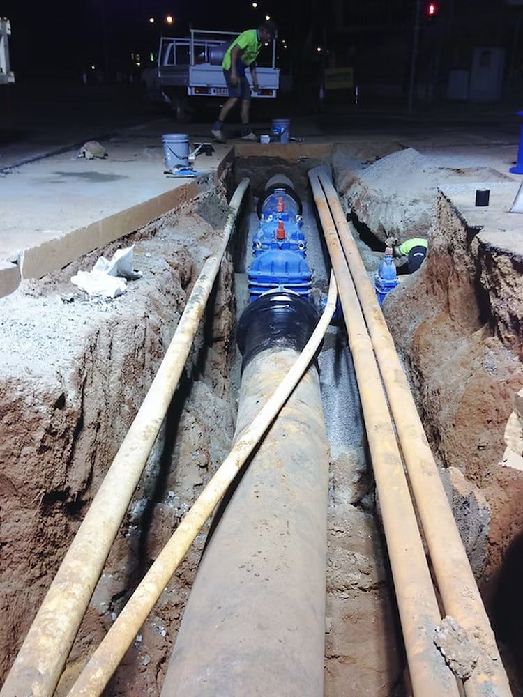 A Man is Working on a Pipe in a Trench at Night — Ausplumb NT in Winnellie, NT