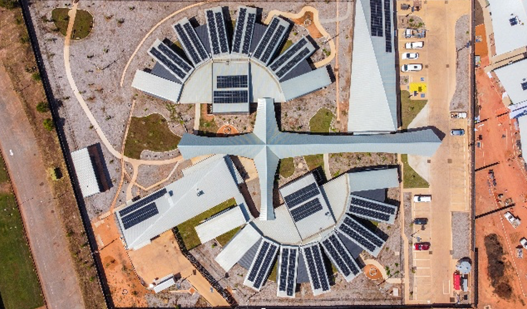 Aerial view of a modern facility with radial wings and solar panels, light-colored roofs, and an adjacent parking lot. — Ausplumb NT in Winnellie, NT