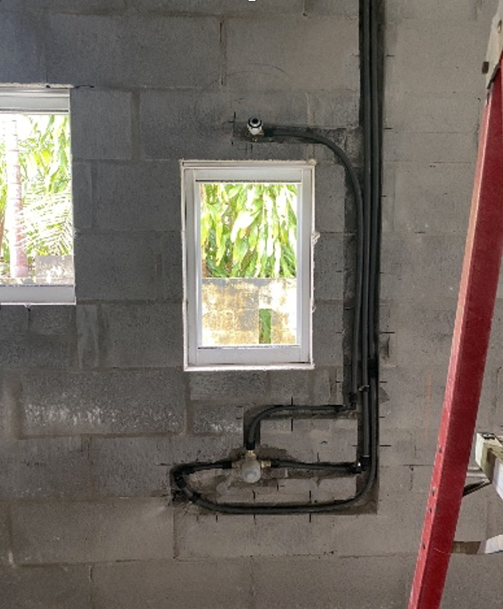 Construction: Plumbing pipes against a gray cinder block wall with windows. — Ausplumb NT in Winnellie, NT