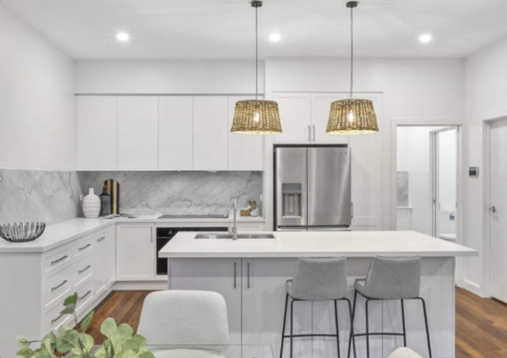 White kitchen with island, marble backsplash, stainless steel appliances, and rattan pendant lights. — Ausplumb NT in Palmerston, NT