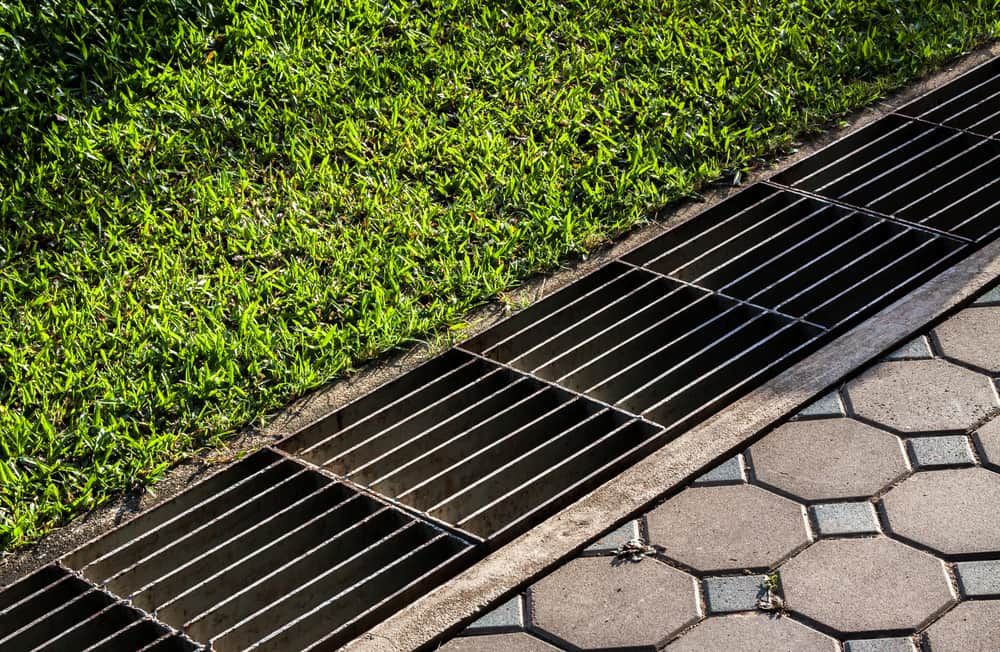 A Metal Drain on a Sidewalk Next to a Grassy Area — Ausplumb NT in Winnellie, NT