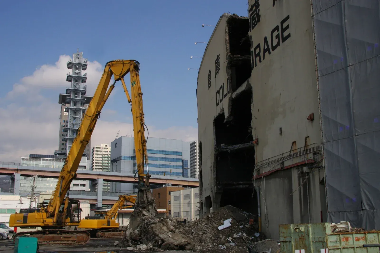 Excavator demolishing a building labeled