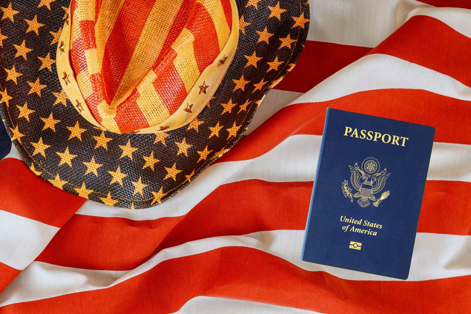 U.S. passport on an American flag beside a straw hat with a patriotic star pattern