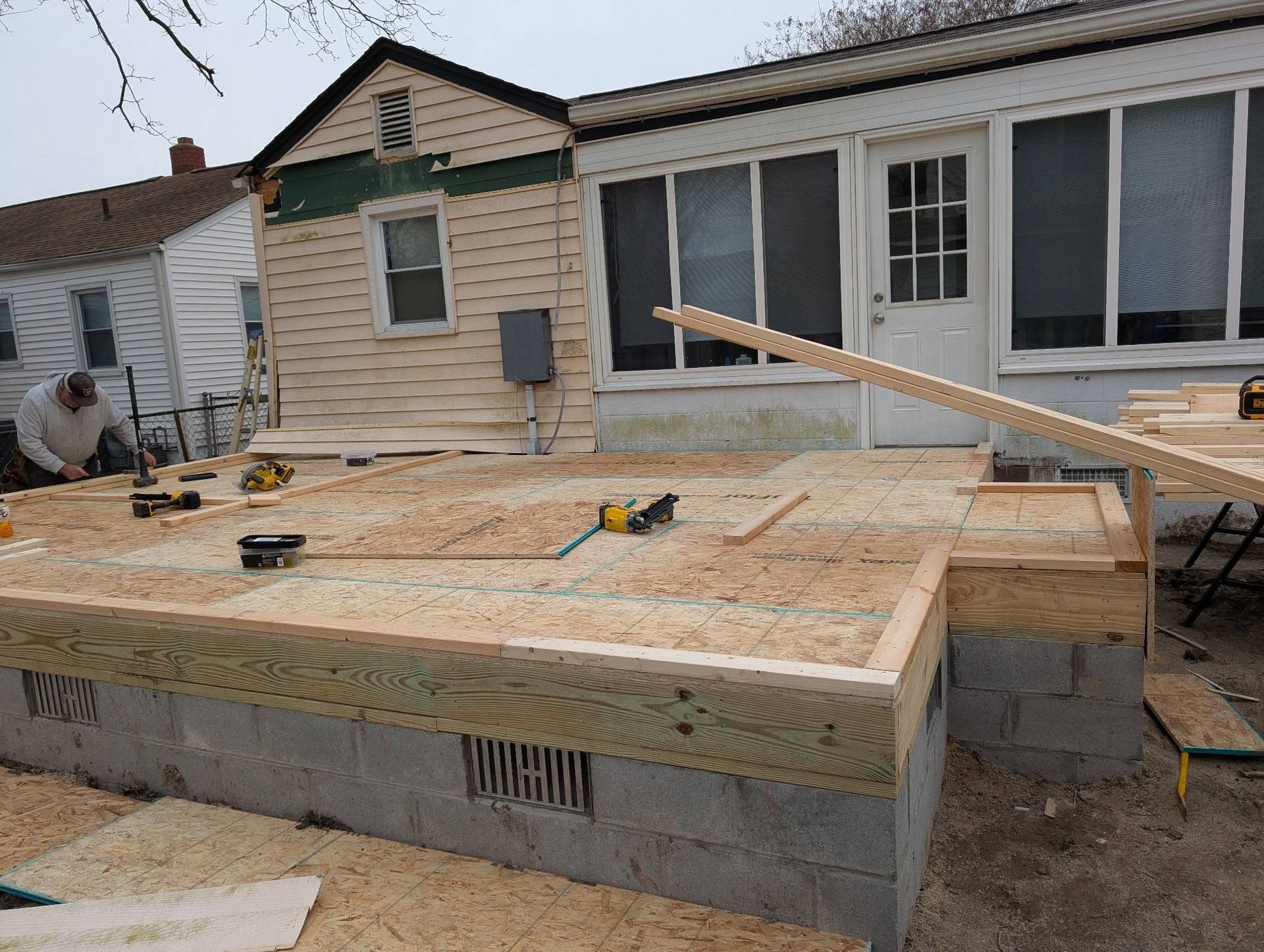 House porch under construction with wooden framing and plywood over cinder block supports