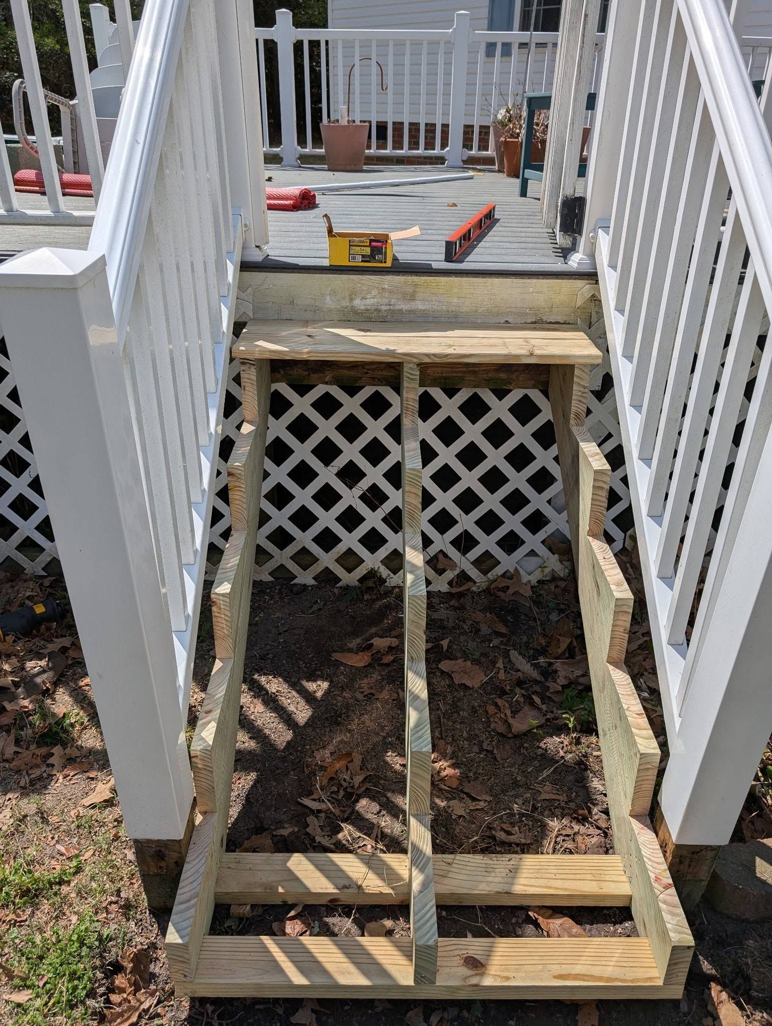 Broken wooden ramp leading to a porch between white railings and lattice skirting