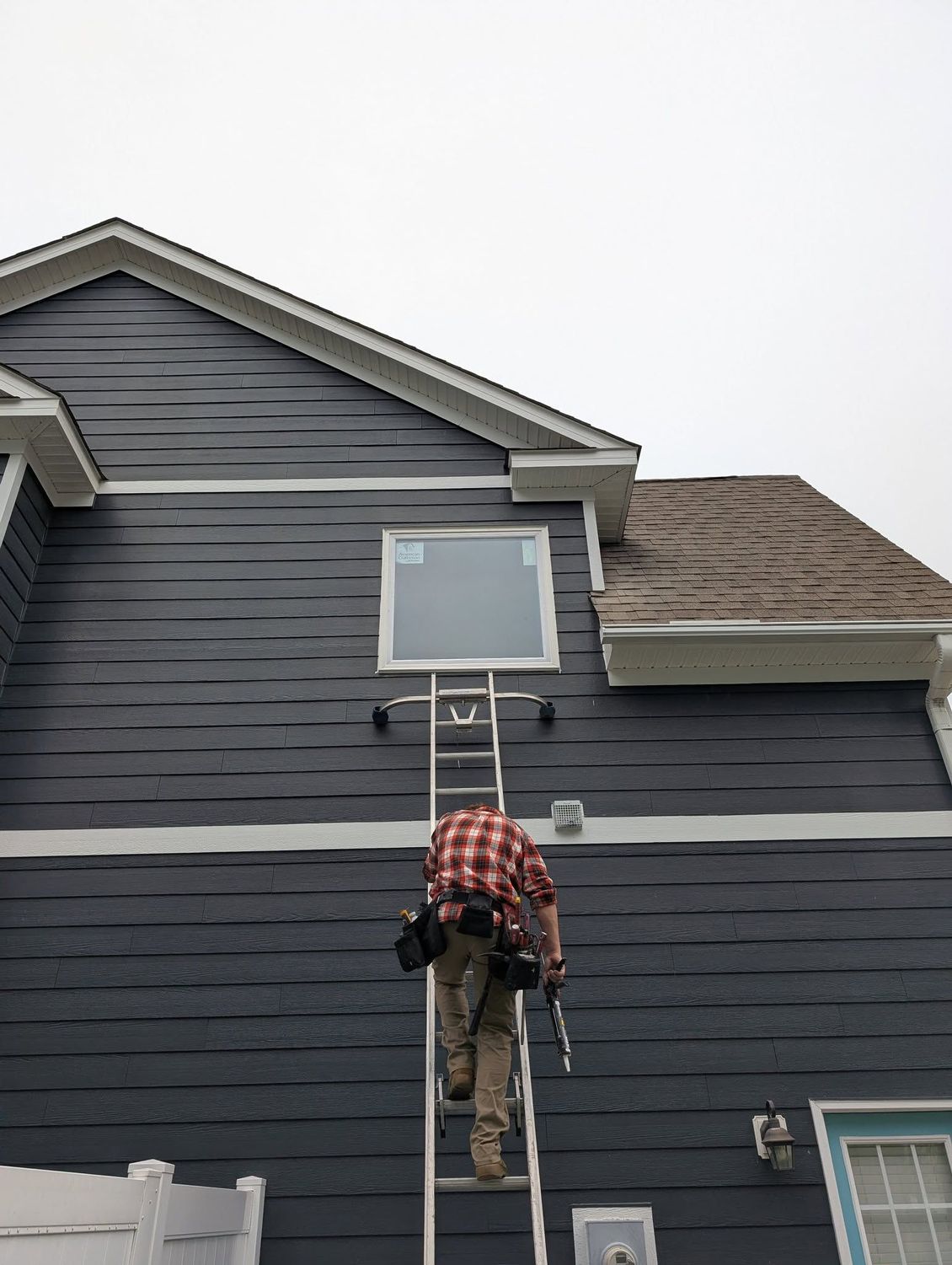 Person working in a backyard, shoveling gravel beside a wooden deck and fence.