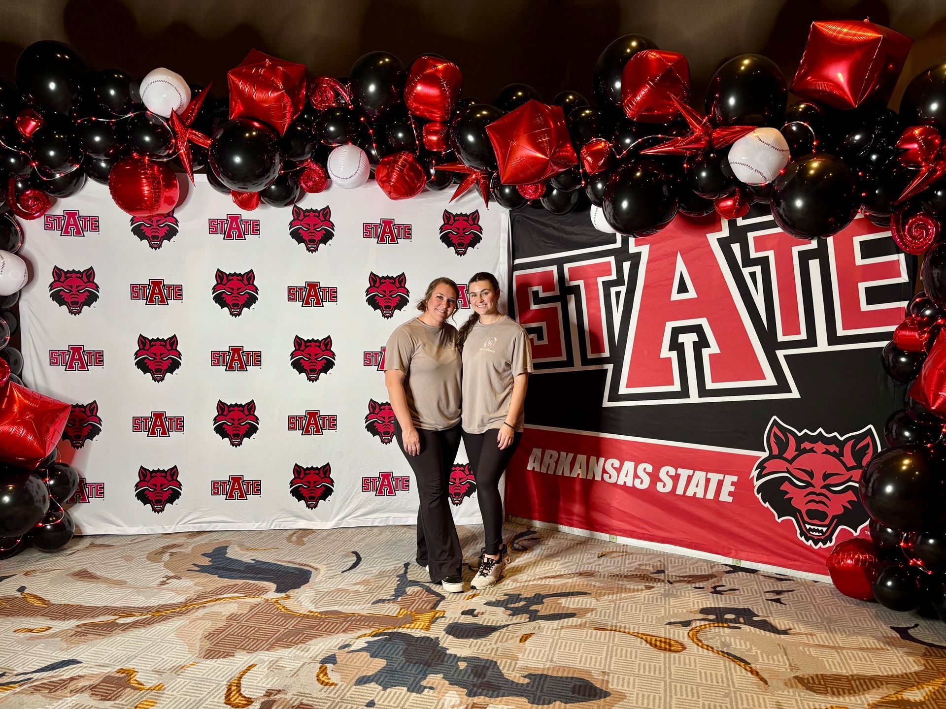 the bloom house owners in front of a state backdrop with matching balloon arch