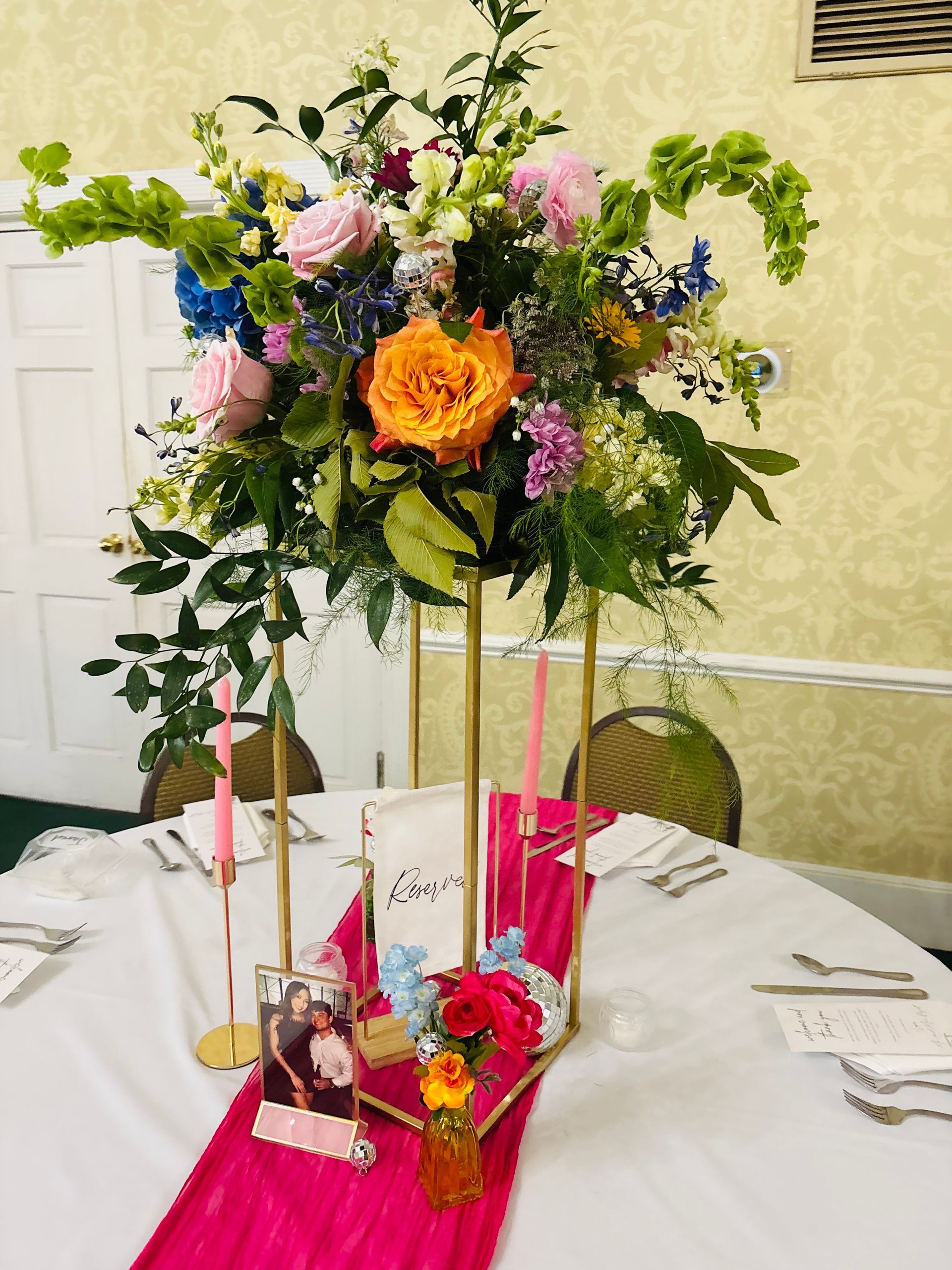 large centerpiece with orange and pink roses and green bells of ireland