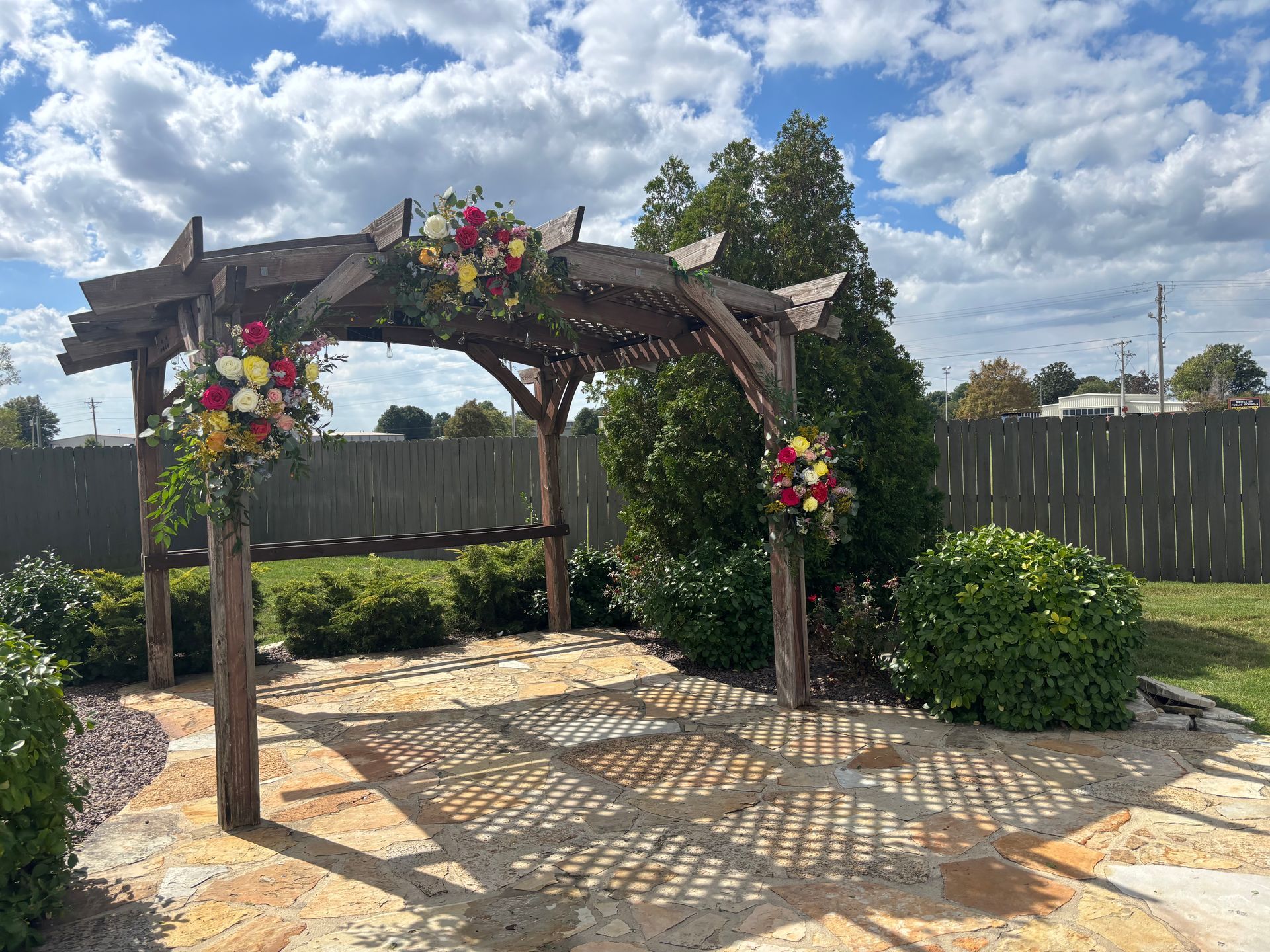 large wooden pergola with red and yellow flowers for wedding