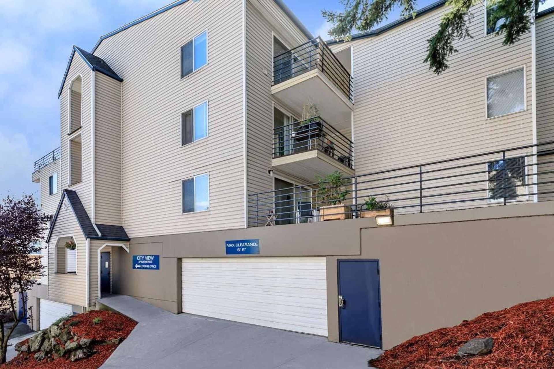 Apartment building exterior with garage, blue doors, and beige siding