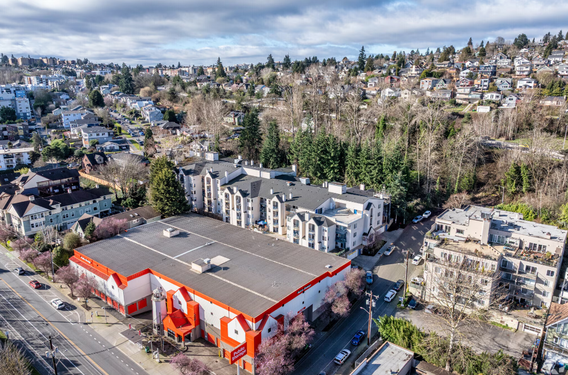 Aerial view of a red-roofed commercial building in a suburban neighborhood with trees and homes nearby