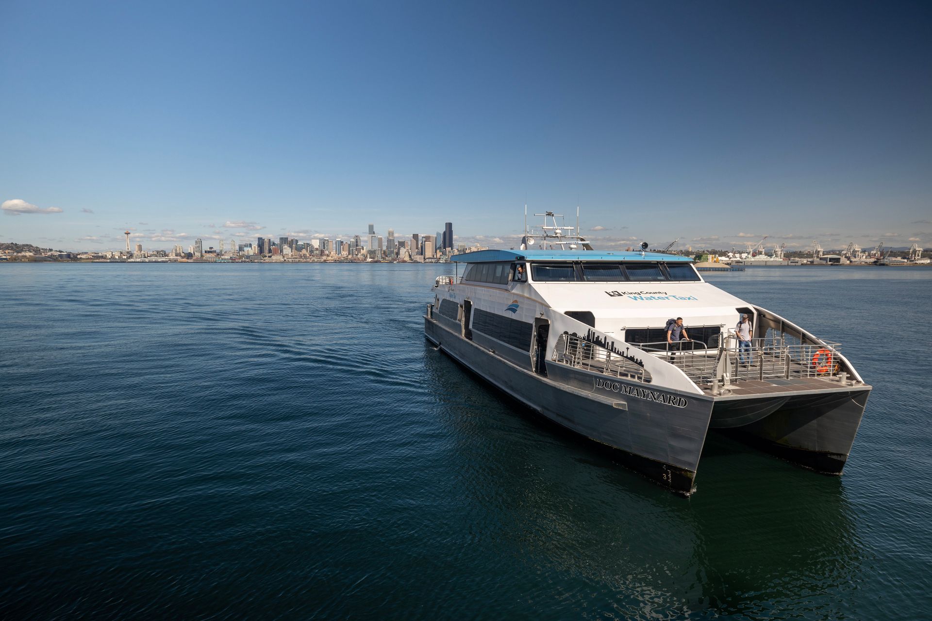 Modern ferry boat on calm water with a city skyline in the distance