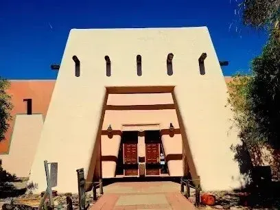 Henderson Artificial Turf-Southwestern-style adobe building with a large entrance, wooden doors, and blue sky in the background.