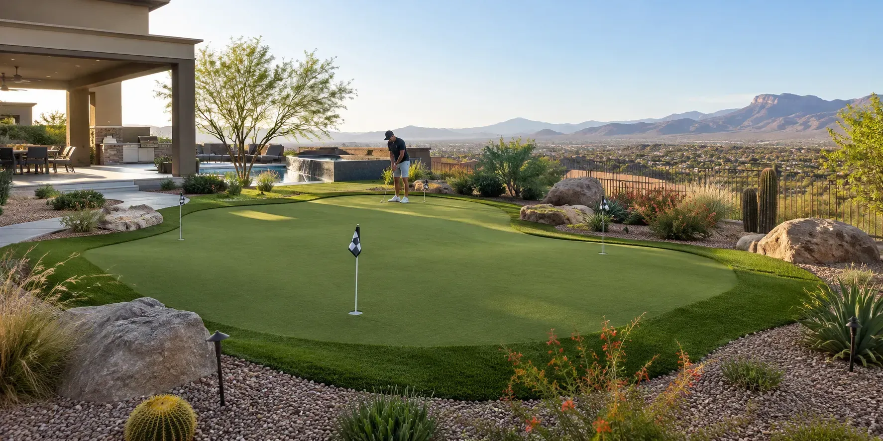 Beautifully contoured backyard putting green surrounded by desert landscaping, boulders, drought-tolerant plants, and mountain views in Henderson, Nevada.