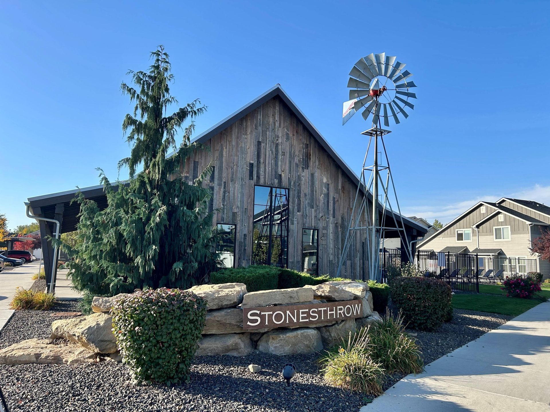 Stone structure with a sign, a windmill, and landscaping.
