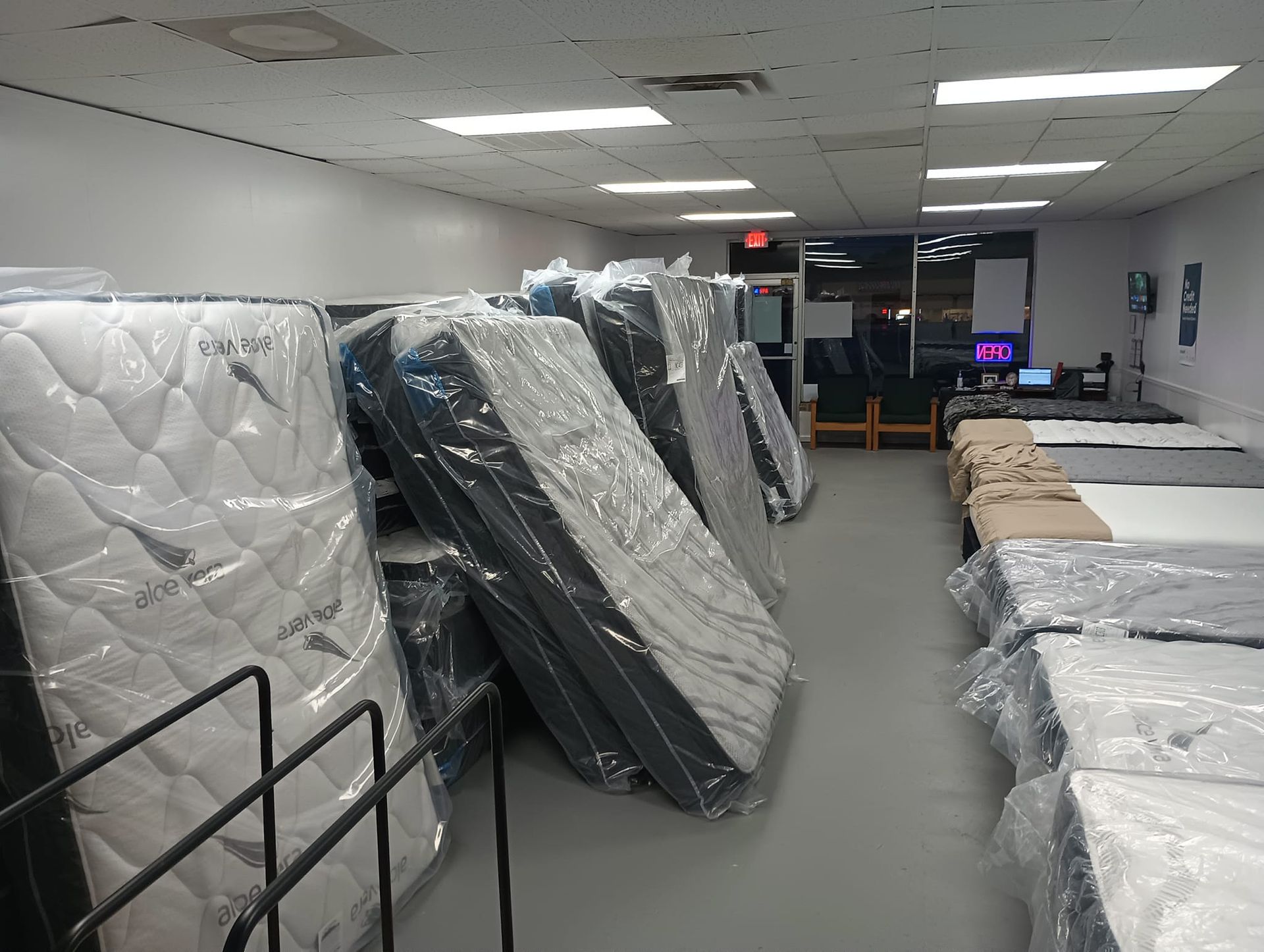 Mattress store interior with rows of wrapped mattresses on display.