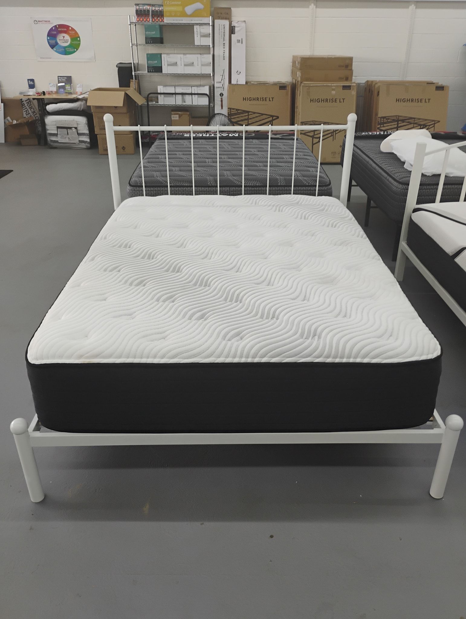 White metal bed frame with mattress in a store.