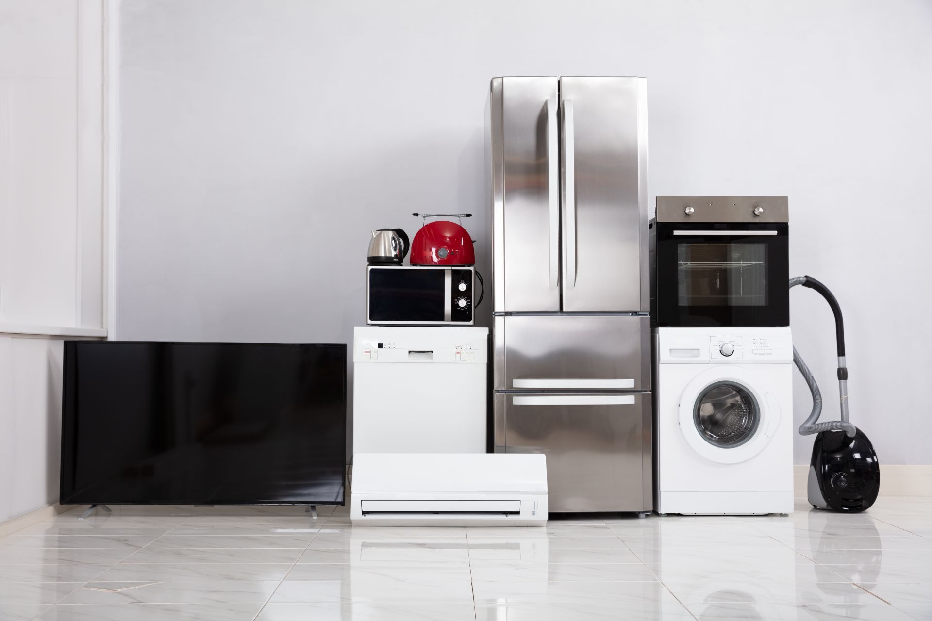 Various household appliances, including a refrigerator, oven, washing machine, and TV, against a white wall.