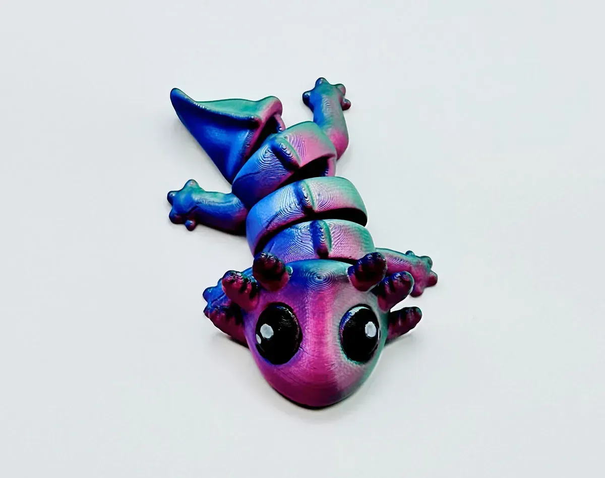 Colorful iridescent cartoon dragon figurine with big eyes on a light background