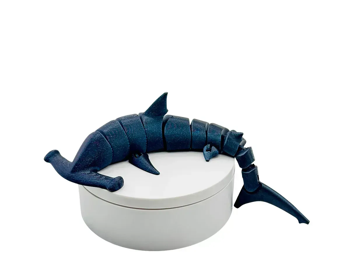 Blue shark plush toy draped over a white round container