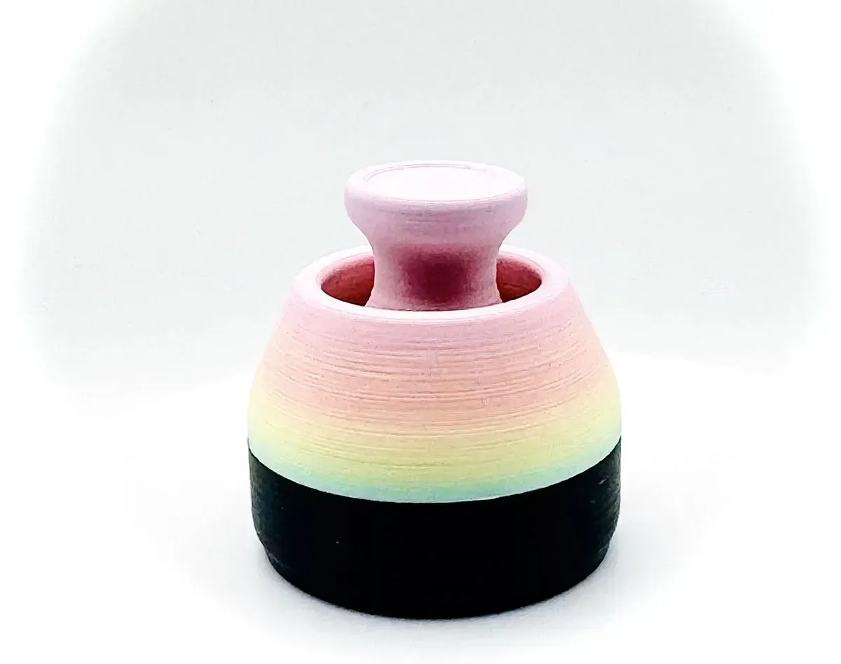 Pastel pink and black foam earplug with a rounded stem on a white background