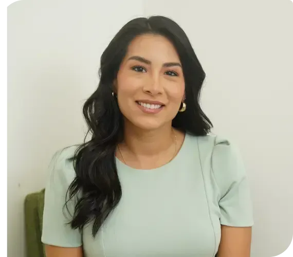 Smiling woman with long dark hair wearing a light green top against a plain white background
