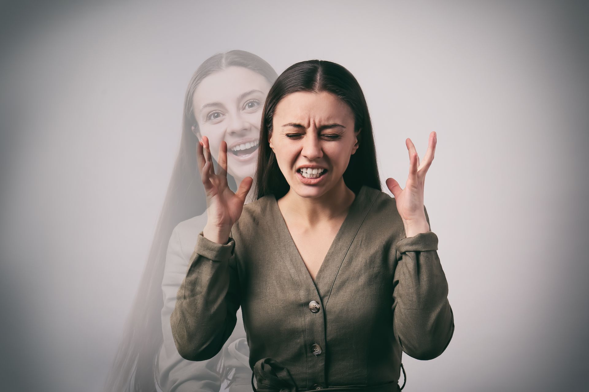 Distressed woman in a gray blouse, eyes closed and hands raised, with a faint ghostly duplicate behind her