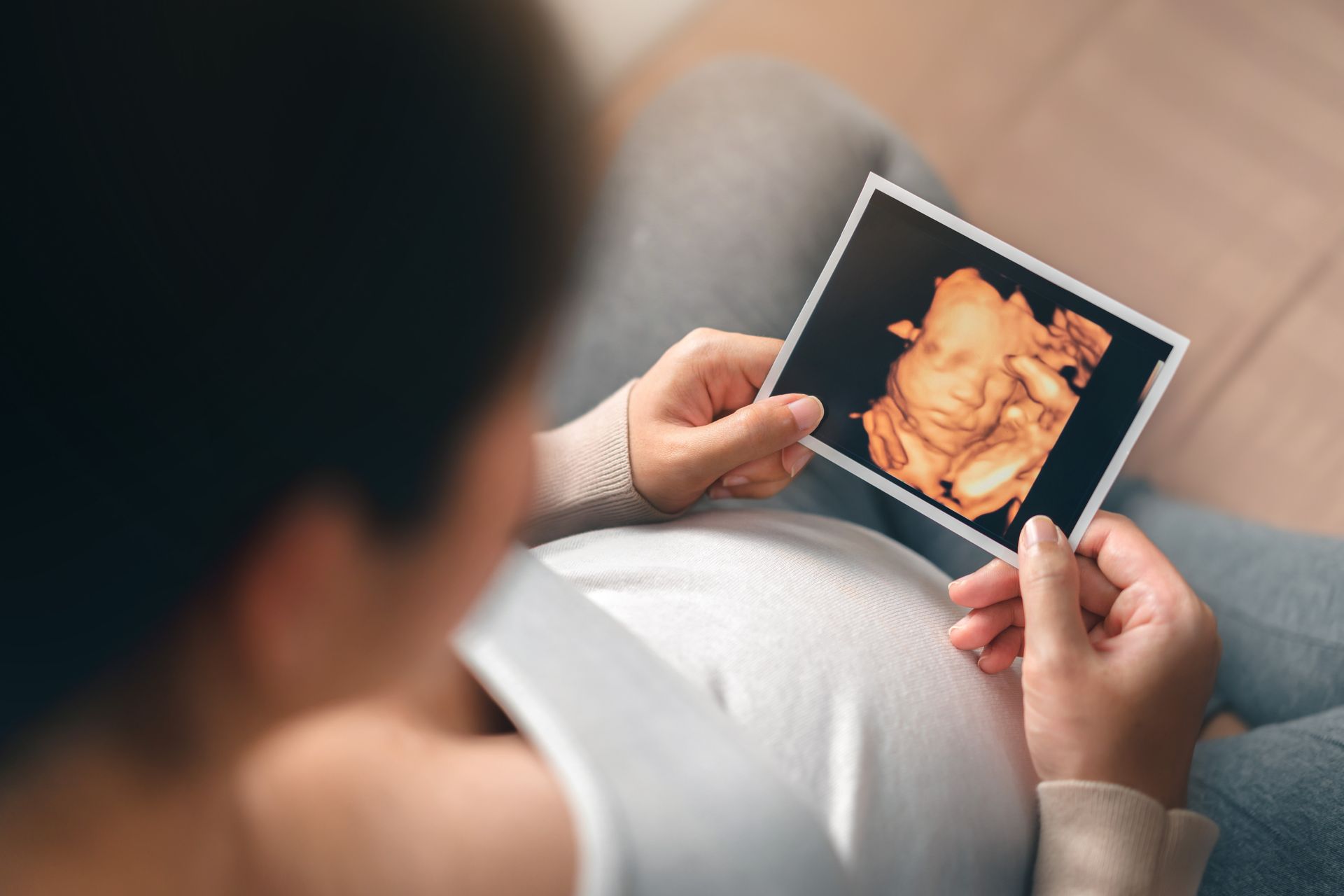 Person holding a sonogram print while sitting on a couch