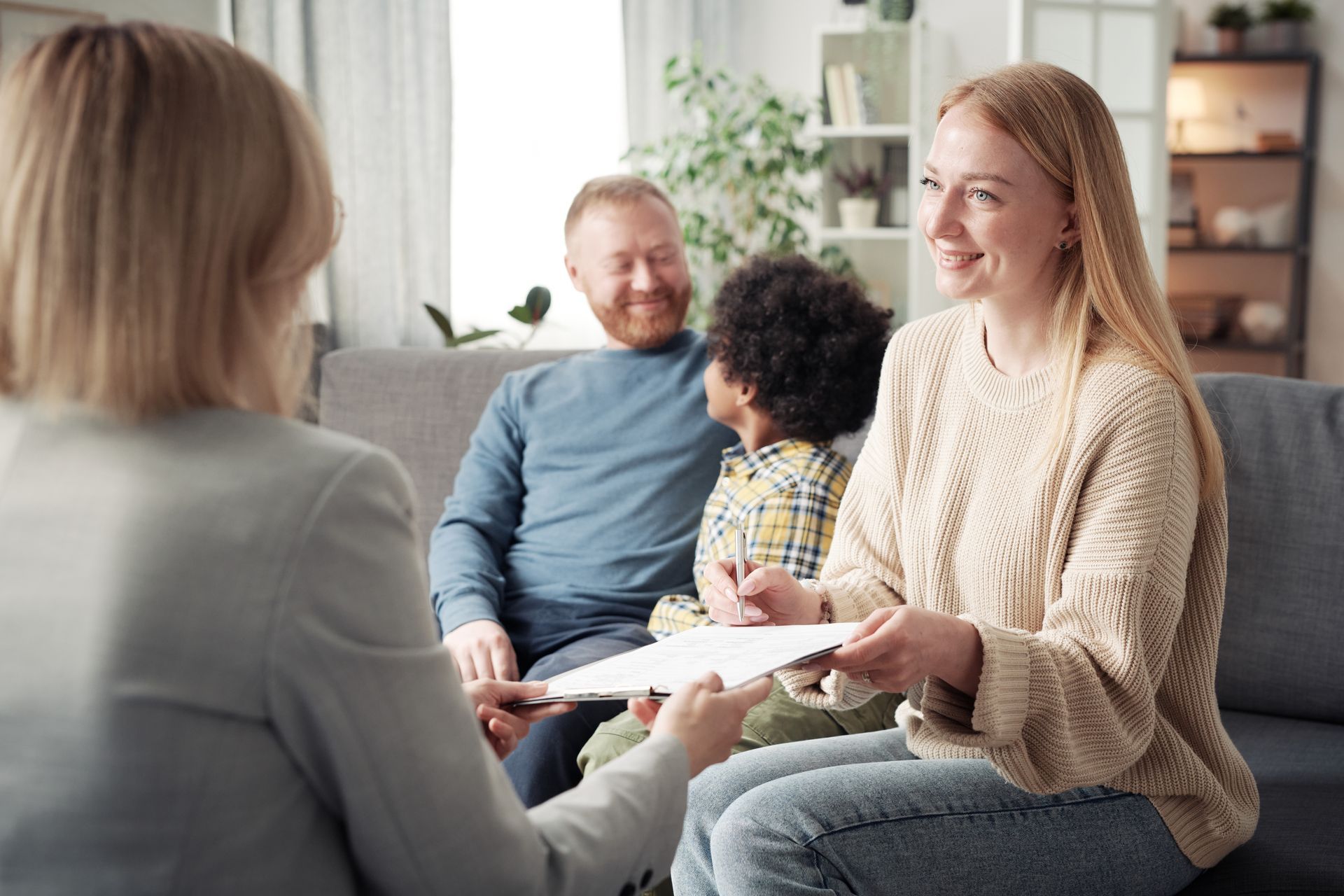 Counselor meeting with a family in a bright living room, discussing papers and smiling together