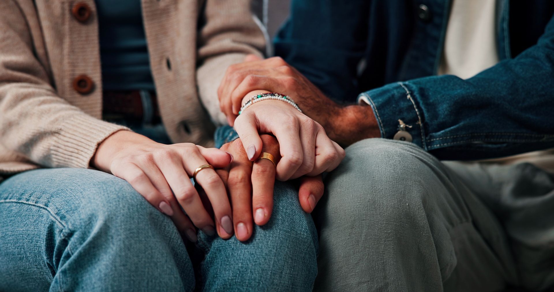 Two people sitting close together, holding hands in a quiet, intimate moment