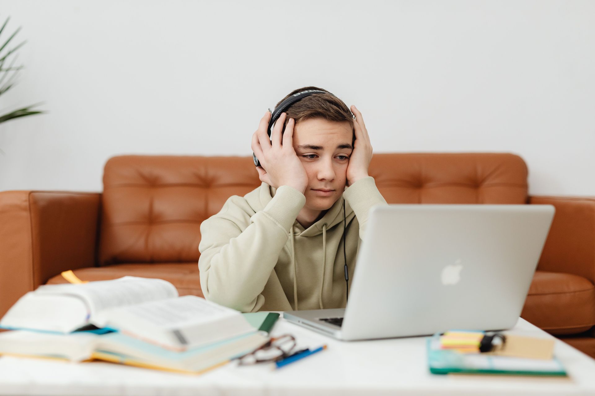 Person resting head on hand while looking at a laptop in a dimly lit room