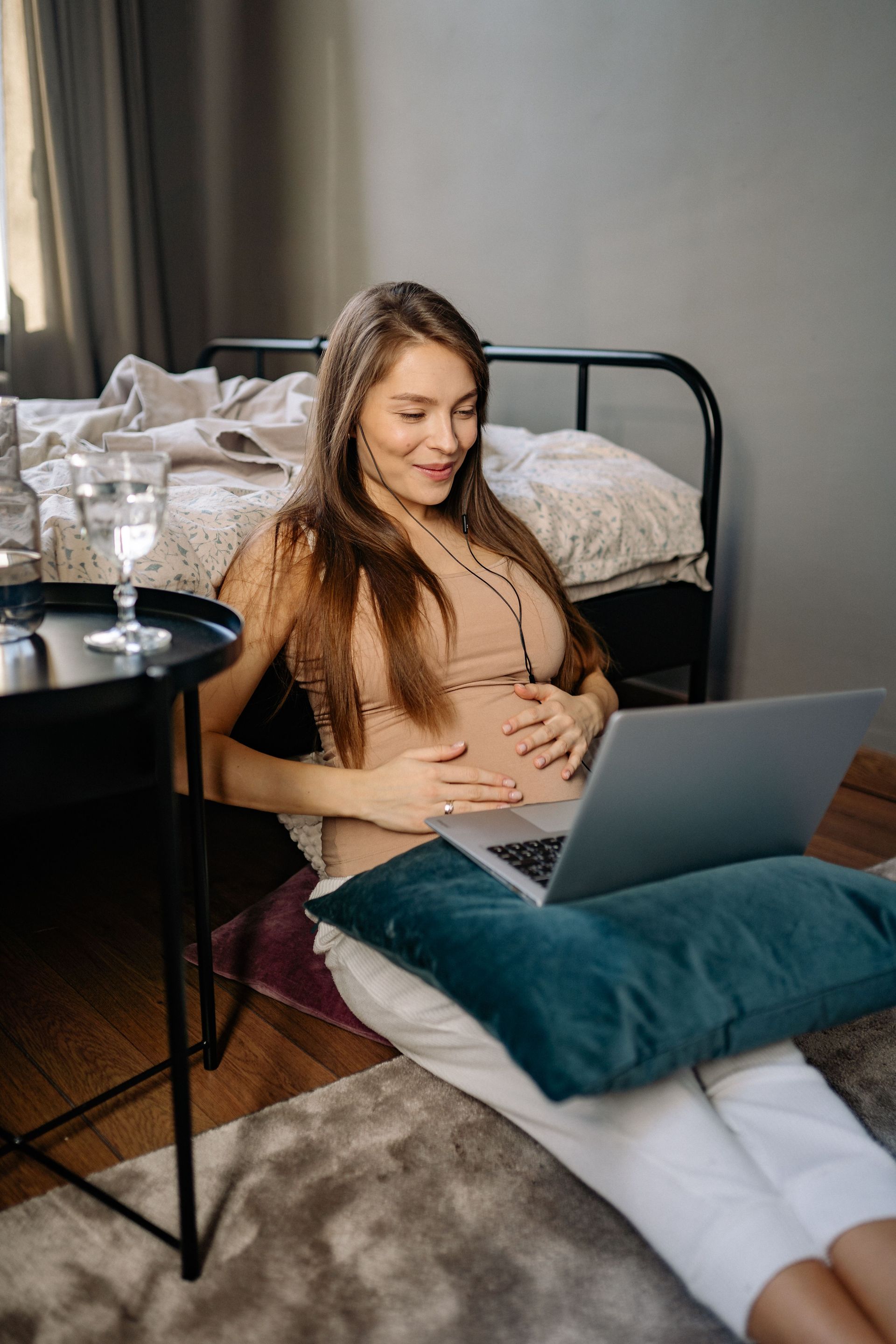 Pregnant person with hands on belly during a supportive conversation on a couch