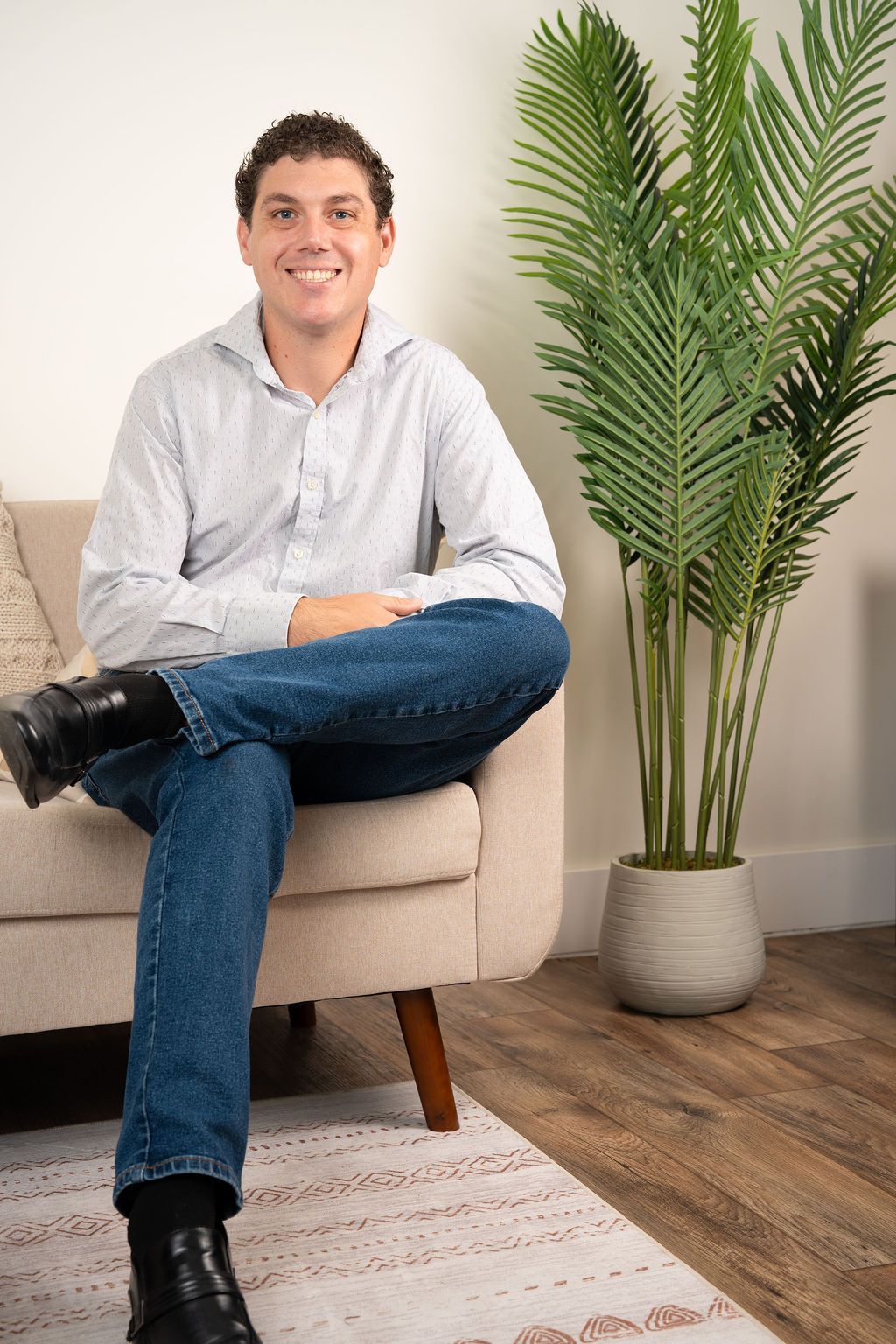 Smiling person in a white shirt seated at a desk in an office chair