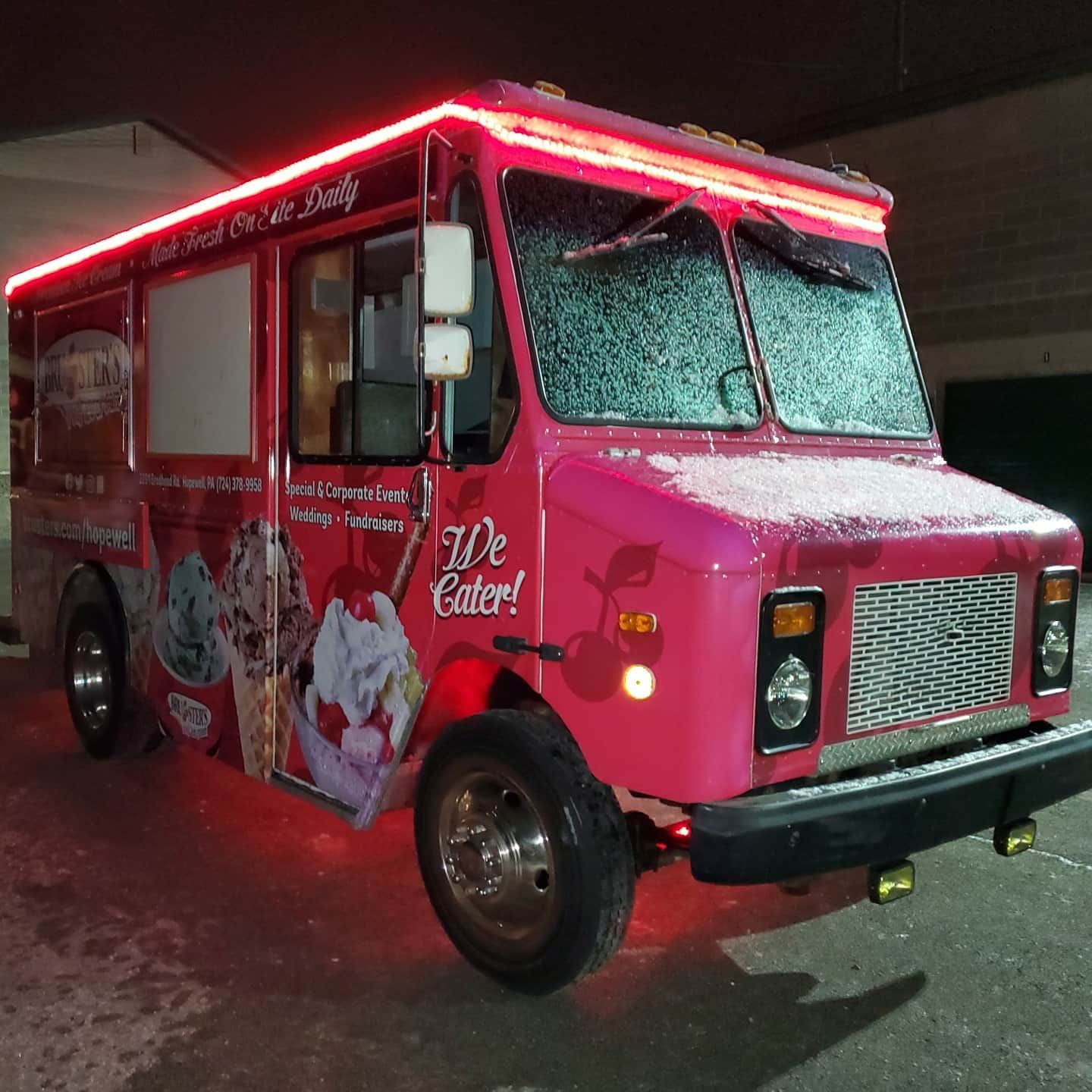 Pink food truck with red lights, advertising ice cream. 