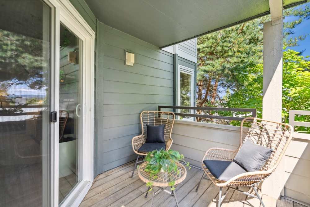 Balcony with two wicker chairs and a small round table on an apartment unit.